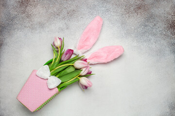 Easter concept. Tulips in the bag and bunny ears on a gray background. Top view. Copy space