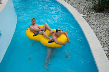Young attractive couple have a rest in the summer in the water park.
