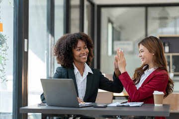 Asian businesswoman and American businesswoman Happy african man clapping with business finance Successful online jobs and achieving goals in the office.