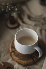 A white cup filled with cappuccino on a wooden stand