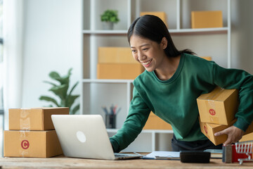 Asian female startup business owner She is checking customer orders on her laptop. by holding a...