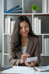 Asian businesswoman recording data using desktop computer keyboard and calculator to analyze marketing strategy and real estate data reduce corporate taxes for clients. Accounting and Tax Concepts