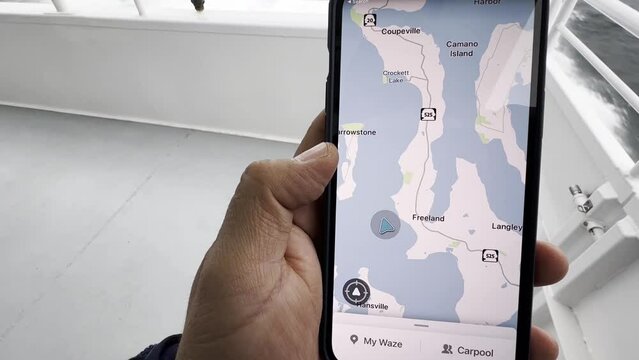 Boat trip across the ocean. A man checks the location on the map app on his smartphone.