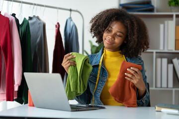 American business woman african, tailor A small business owner is selling clothes online, an online ordering app through a colorful laptop computer to customers at his home office.