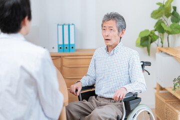 医者と話す高齢の患者（車椅子・介護）