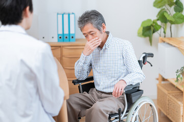 医者と話す高齢の患者（車椅子・介護）
