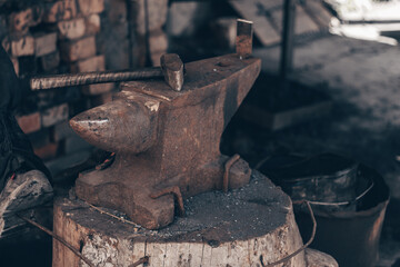 Process metal with hammer on anvil in forge. Strike iron outdoors in workshop with fire. Metalworking, blacksmithing, manufacturing equipment and tools. Traditional technic of making hardware.