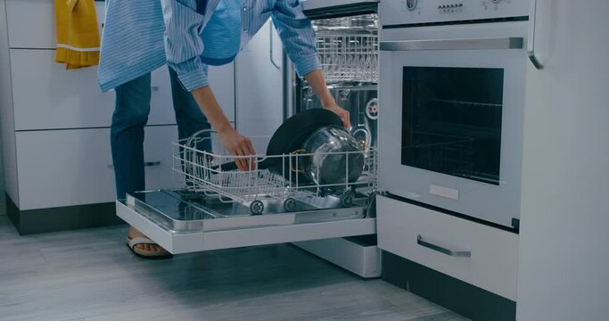 Woman placing frying pan into the dishwasher close-up shot