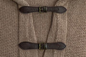 Leather clasp on beige knit. Needlework and creativity. Close-up.