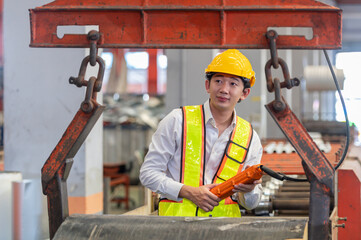 Asian male engineer in uniform inspection warehouse and check control heavy machine construction installation in industrial factory. technician worker check for repair maintenance operation system