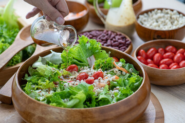 Hand chef mix fresh baby cos salad millet Crab Stick and pour salad dressing in wood blow. Organic Vegetables mix lunch with green salad In bowl. Breakfast fresh salad and clean vegetable