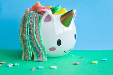 cute vase in the form of a unicorn with gummy bears on a colored background