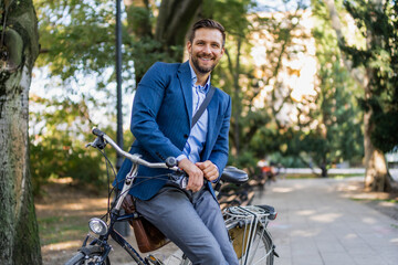 A young smiling, stylish men posing leaned on his bicycle.