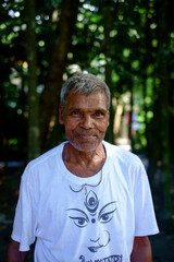 portrait of a south asian senior person wearing white t shirt on which art of goddess durga is drawn, smiling face from a religious festival 