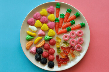 Naklejka na ściany i meble a lot of multi-colored sweet gummies on a large flat plate on a pink-blue background