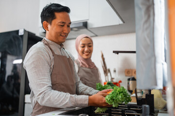 happy young muslim couple making food together at home