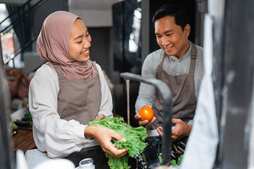 happy muslim husband and wife enjoy cooking food together in the kitchen