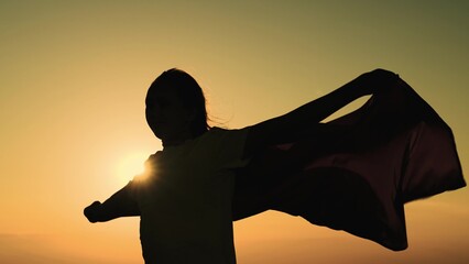 girl superhero sunset glare. game teenager red raincoat top mountain. glare sun sky. brave...
