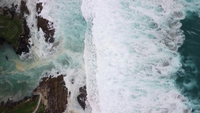 Topdown View Of Rough Ocean With Foamy Waves Crashing Over Cliffs In Caion Beach In Coruna, Spain. Aerial Drone Shot