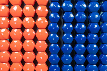 Close-up picture with sports dumbbells of different colors and weights. Inventory for practicing physical narzuks and increasing muscles in the arms.