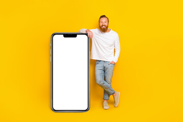 Full length photo of beard man near big telephone wear shirt jeans shoes isolated on yellow color background