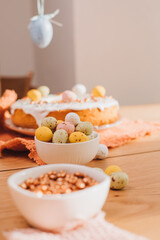Round Easter cupcake decorated with white protein cream and colorful sprinkles on a wooden table in the kitchen. Front view