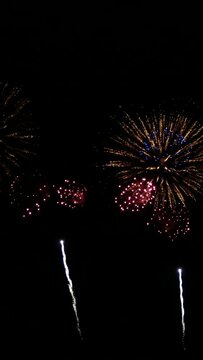 vertical footage of seamless looping of real firework background during new year's eve countdown celebration, real colorful shining big fireworks festival in the sky display at night. glowing firework