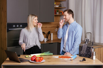 Cooking lunch together. Young pretty woman and man are tasting meal in kitchen.