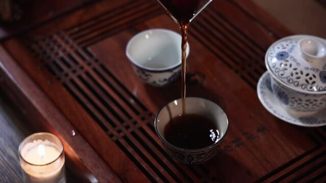 traditional Chinese ceremony, woman hand pours hot puero into bowls on a table with tea accessories, close-up
