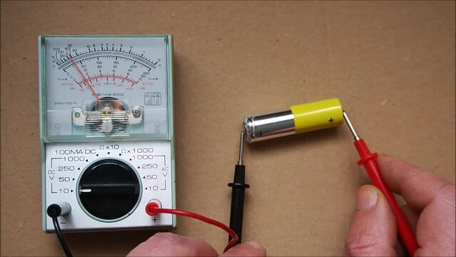 Battery test with analog voltmeter.. Electrician with multimeter. Focused on the dial plate.