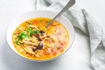 Tomato egg drop soup  with mushrooms and spring onions in a white bowl