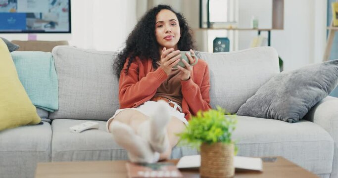 Woman relax on couch, coffee and watching tv, happy and content, drink and entertainment with remote control. Female at home with smile, hot beverage and break, chilling and online streaming service