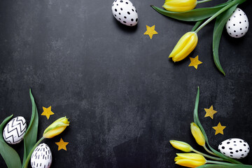 bouquet of yellow tulips and white easter eggs, coffetti stars in gold color on a black background. top view. copy space