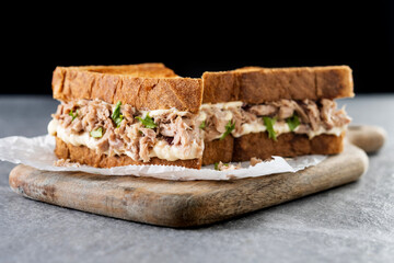 Tuna sandwich with mayo and vegetables on gray stone background.