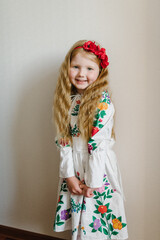 Portrait of a girl dressed in Ukrainian folk embroidered dress. A child with wreath of poppies on his head. National ethnic traditional costume or dress. Ukrainian girl, Ukrainian customs, traditions.