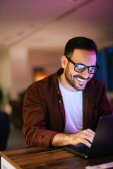 Happy man talking online with a colleague, using a laptop.