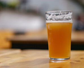Selective focus shot of a glass of beer on a wooden table in a restaurant