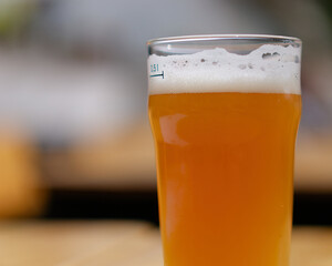 Close-up shot of a glass of beer on a wooden table in a restaurant with a blurry background