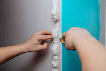 An approximate image of a man's hand cutting foam from the wall with a small stationery knife. Carrying out construction works.