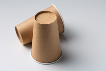 Disposable cardboard biodegradable cups on a white table, gray background.