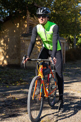 Fototapeta premium A man in clothes stands with a bicycle on an autumn sunny day. Cyclist in an urban environment.