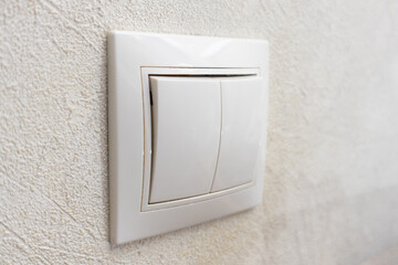 Electric light switch on the background of light textured wallpaper, close-up view, copy space