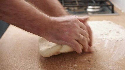 Male hands kneading dough, baking preparation closeup. Pastry Man kneads making yeast dough for pizza, burger, buns, muffins or pie. Anonymous baker. Bakery chef cooking bake in a kitchen professional