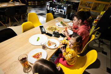 Four kids eating italian pizza in pizzeria. Children eat at cafe.