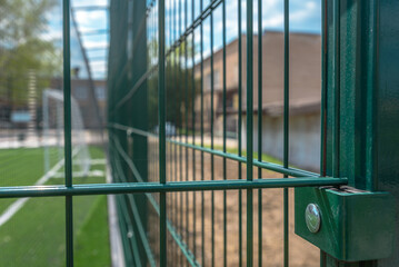 School sport yard with football court surrounded with metal protective fence.