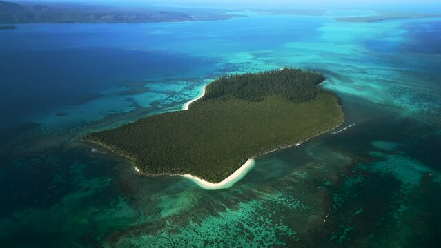 Aerial parallax over island Ilot Brosse (Brush island), surrounding coral reef, New Caledonia.