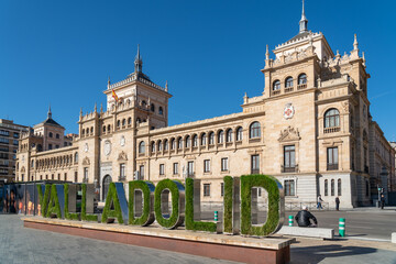 Fototapeta na wymiar Cavalry Academy building in the center of Valladolid, In front is written the name of the city written decorated with grass an flowers. Plaza de Zorrilla Square