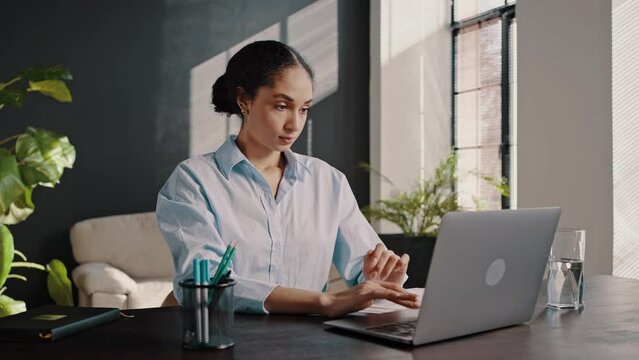 Purposeful woman closing the lid on laptop and massaging her neck after hard working day in office
