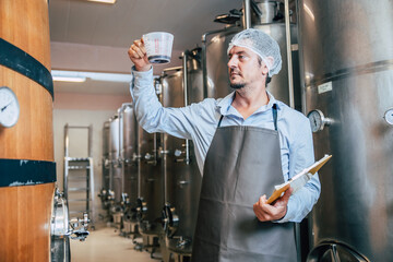 Winemaker working in modern large winery factory liquor drink industry quality and fermentation...