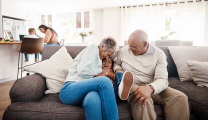 Tickle, laughing and child with grandparents on sofa of living room for bonding, happy family and...